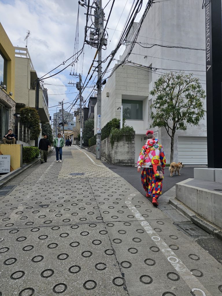Calle de Harajuku en Tokio con un hombre vestido de colores caminando entre tiendas y ambiente urbano