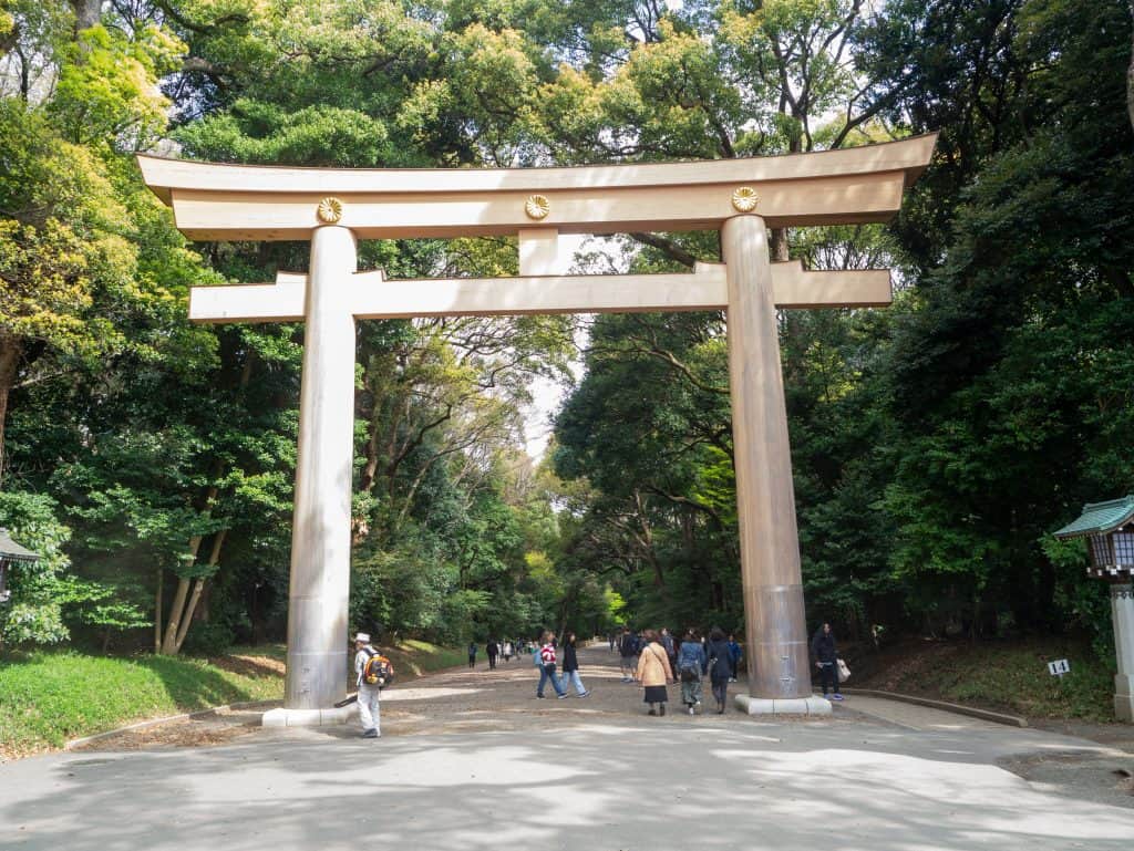 Gran torii de madera en la entrada de Meiji Jingu, rodeado de árboles en Tokio