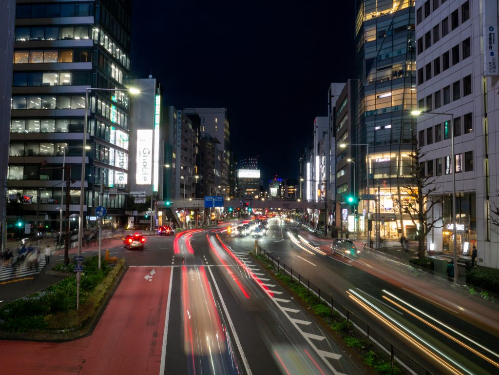 Avenida en Tokio de noche con tráfico y luces largas, ejemplo del ritmo urbano japonés.
